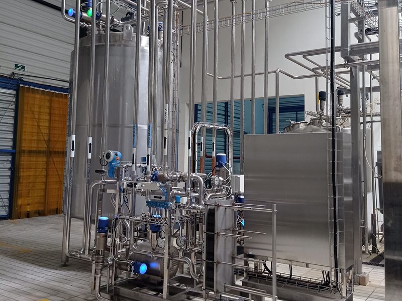 Sistema de recuperação de produto com tanque de aço inox, trocador de calor a placas e tubulação identificada