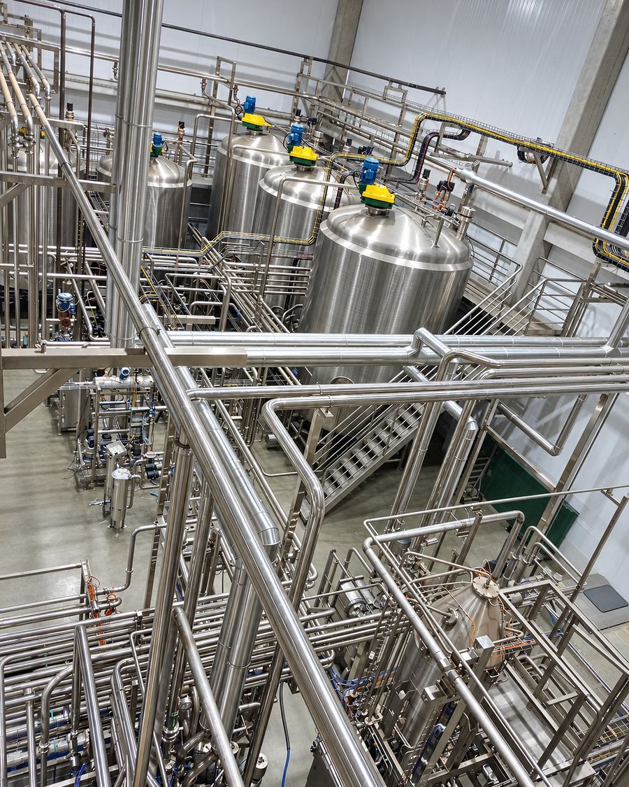 Planta industrial com tanques de aço inox e tubulação sanitária vista de cima